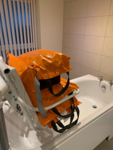 A Bath hoist chair displaying weight bags, indicating weight testing.